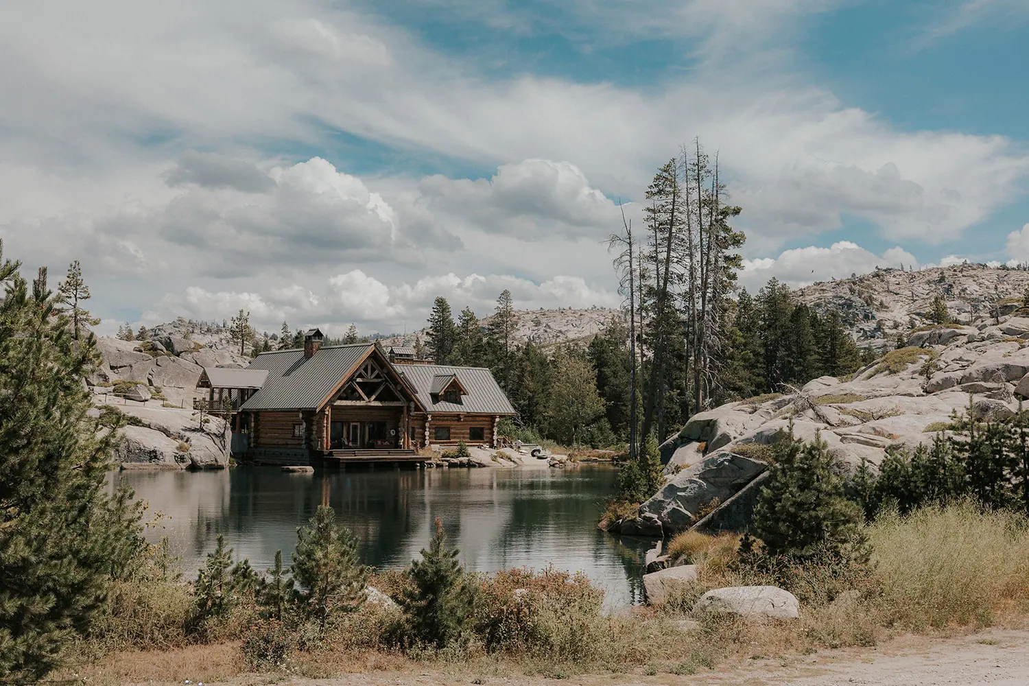 The lodge on its lake, seen from the granite across the water.